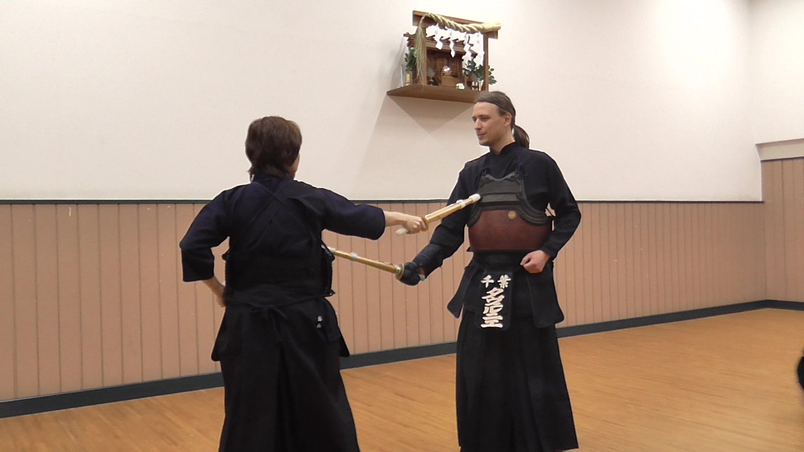 Tankendō practitioner thrusts a short wooden practice sword toward a partner wearing chest armour.